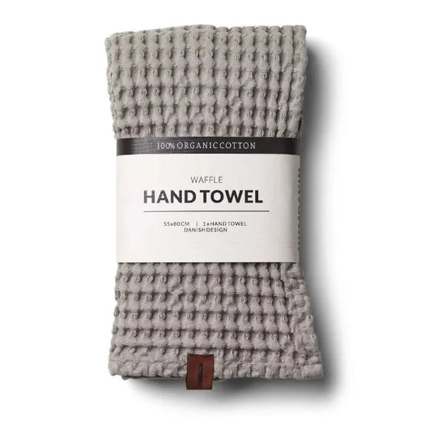 A DWR waffle hand towel displayed on a bathroom counter. The towel features a textured waffle weave pattern, enhancing its absorbency and providing a stylish, contemporary look. Its soft, high-quality fabric and neutral color make it both practical and elegant for everyday use.