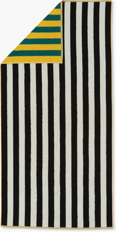 A vibrant Dusen Dusen striped beach towel in the Chincoteague pattern, spread out on sandy beach. The towel features bold, colorful stripes in various widths, creating a playful and eye-catching design. Made from soft, absorbent fabric, it’s perfect for lounging by the water or drying off after a swim, adding a stylish flair to any beach day.