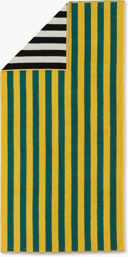 A vibrant Dusen Dusen striped beach towel in the Chincoteague pattern, spread out on sandy beach. The towel features bold, colorful stripes in various widths, creating a playful and eye-catching design. Made from soft, absorbent fabric, it’s perfect for lounging by the water or drying off after a swim, adding a stylish flair to any beach day.